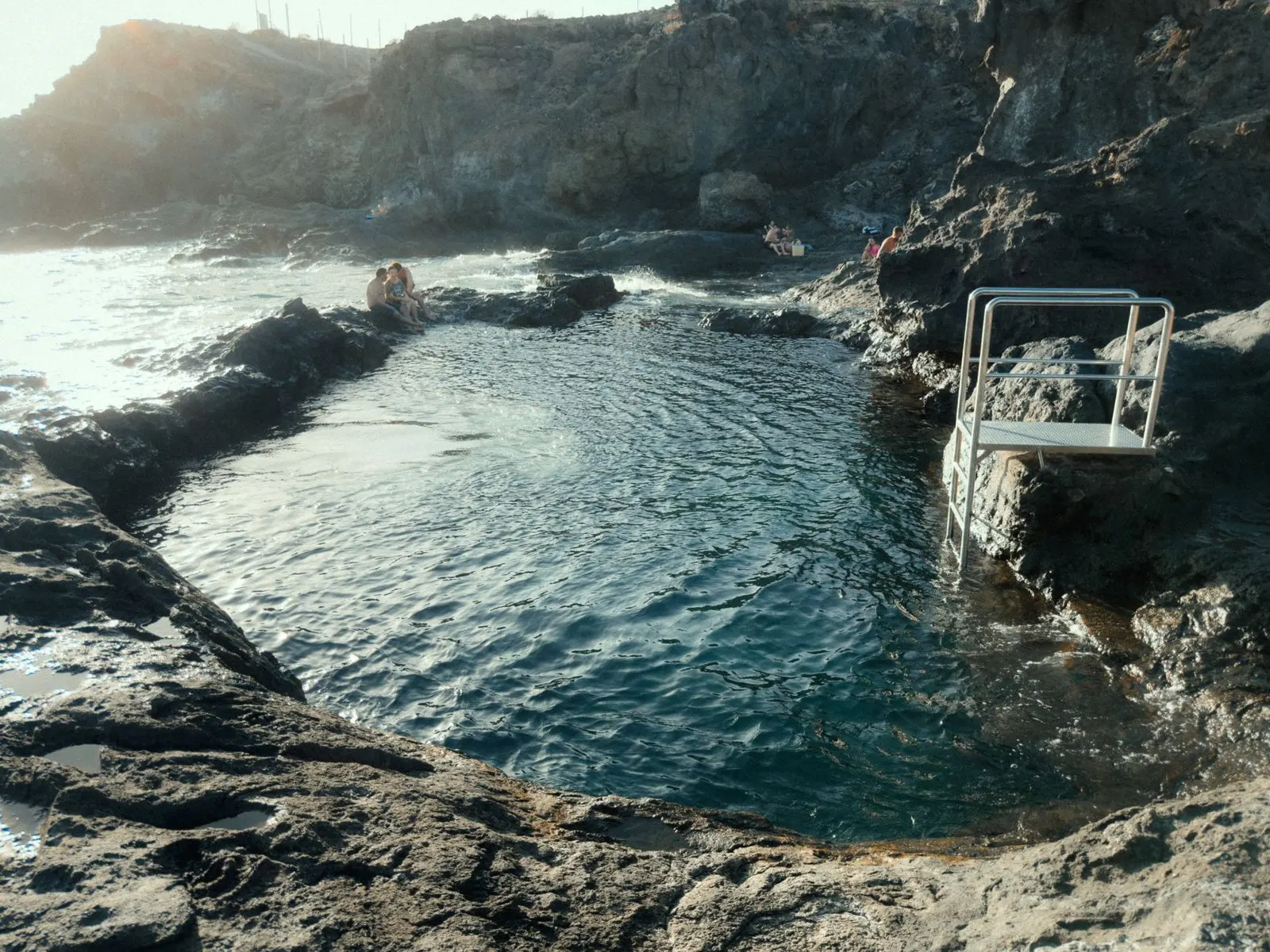 Natural lava pond with swimmers and an access ladder